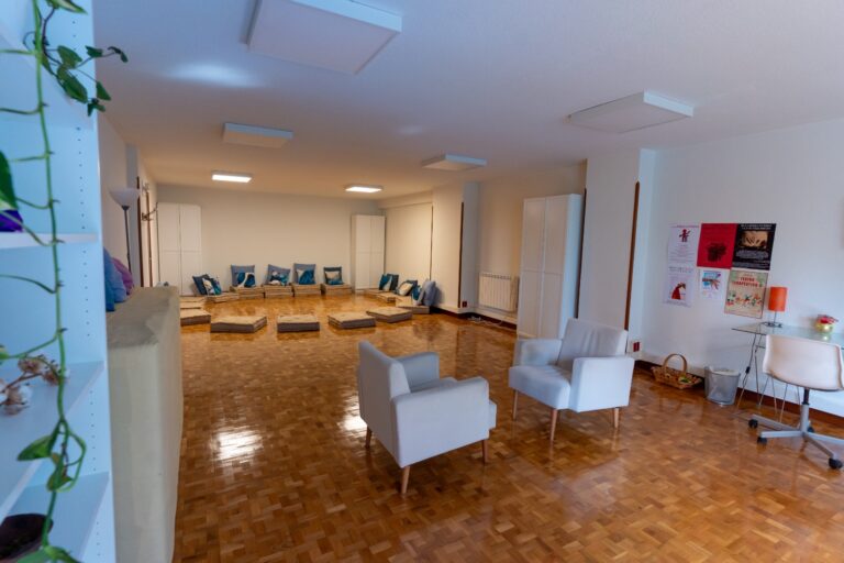 La sala de grupo de Argos vista desde la entrada, con cojines en el suelo, dos sillones y el tablón de talleres